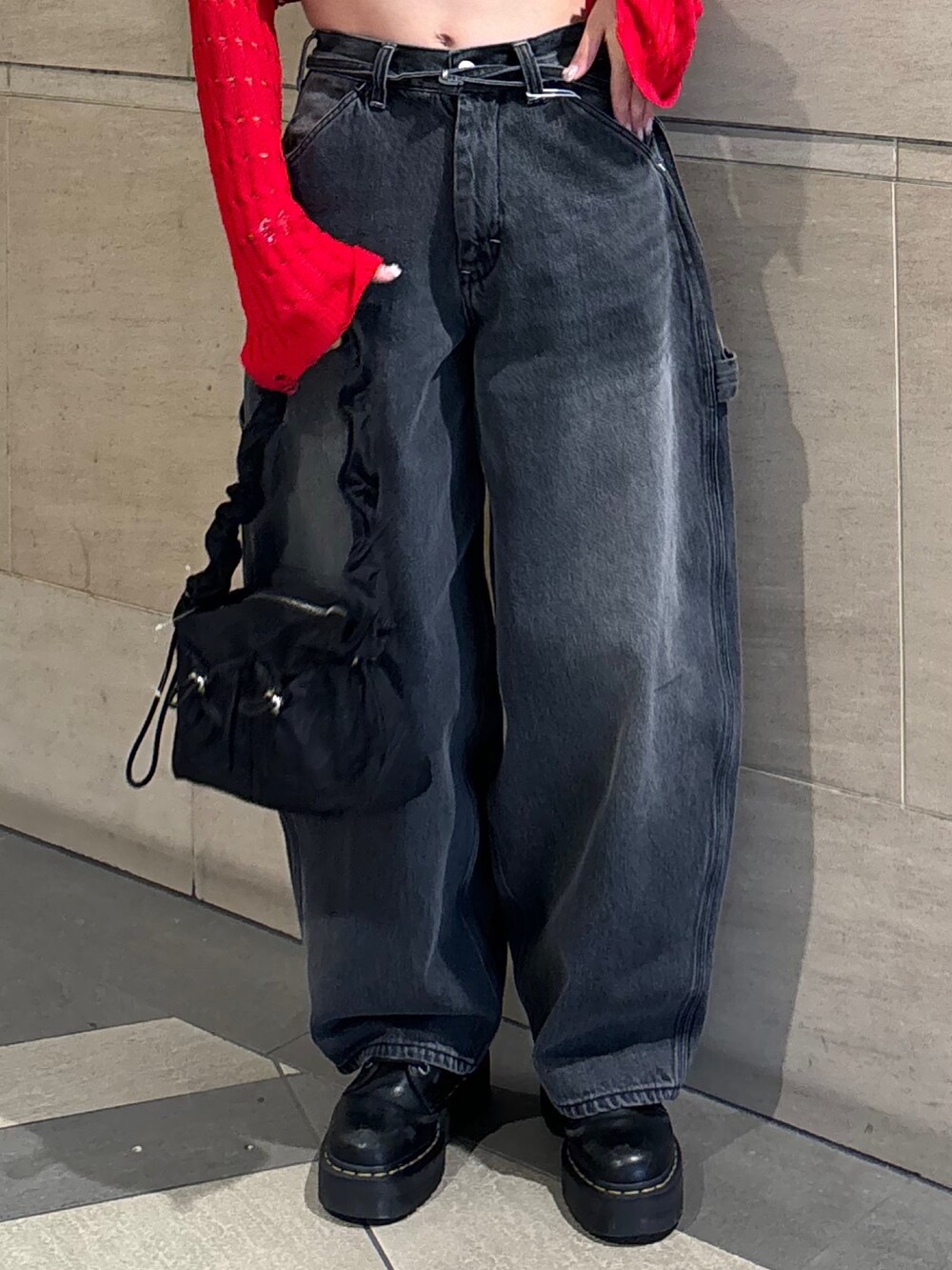 ブラック系のデニムパンツ、ブラック系のショルダーバッグ、レッド系のニット/セーターを着用したレディースの春コーディネートの9枚目の写真