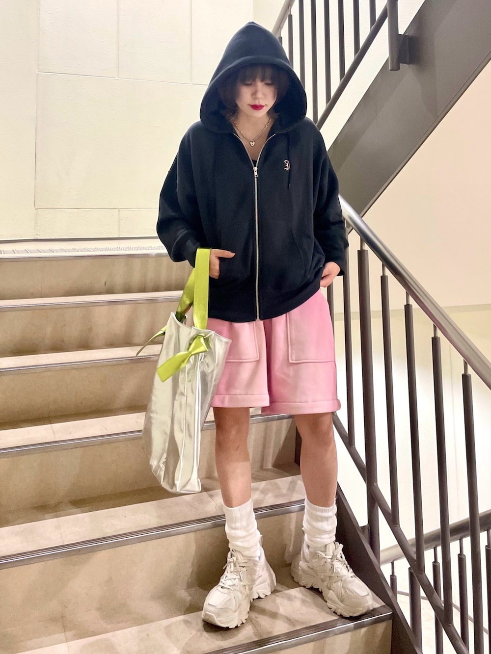 シルバー系のトートバッグ、ピンク系のスウェットパンツ、ブラック系のパーカーを着用したレディースの冬コーディネートの3枚目の写真