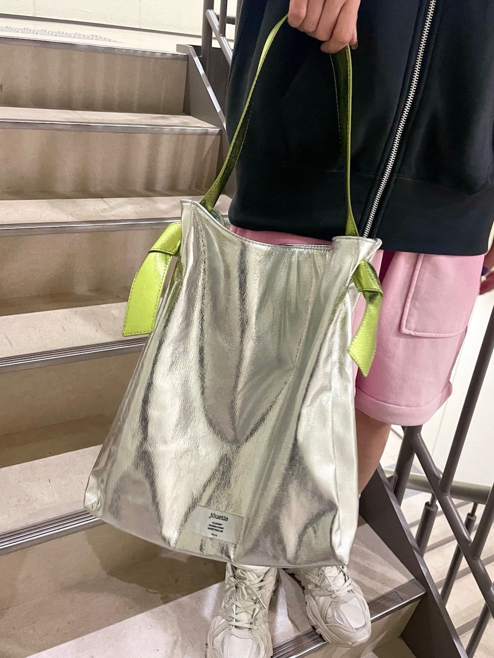 シルバー系のトートバッグ、ピンク系のスウェットパンツ、ブラック系のパーカーを着用したレディースの冬コーディネートの8枚目の写真