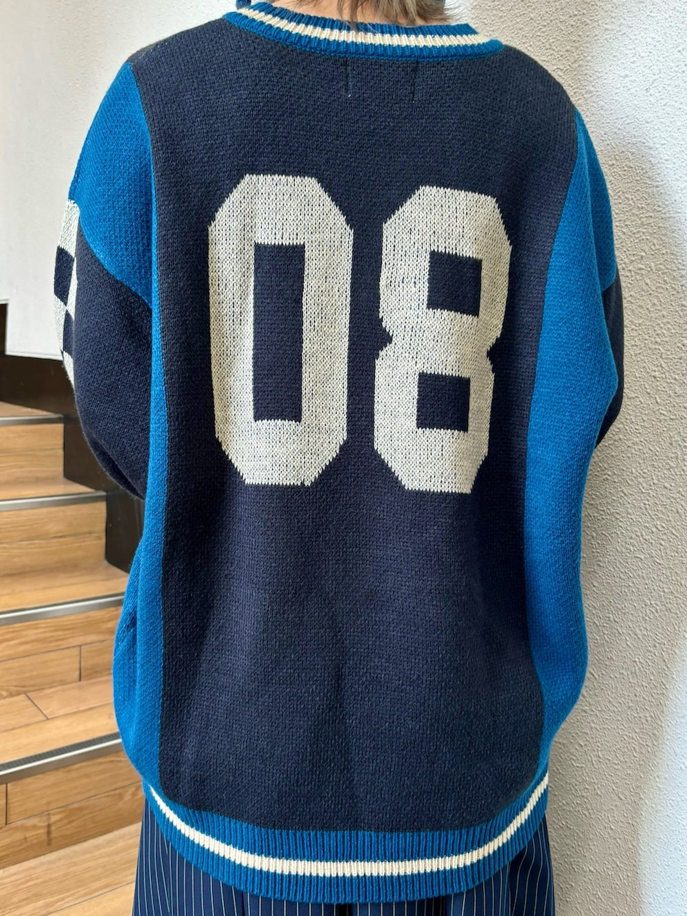 ブルー系のスカート、ゴールド系のハンドバッグ、ブラック系のニット/セーターを着用したレディースの夏コーディネートの7枚目の写真