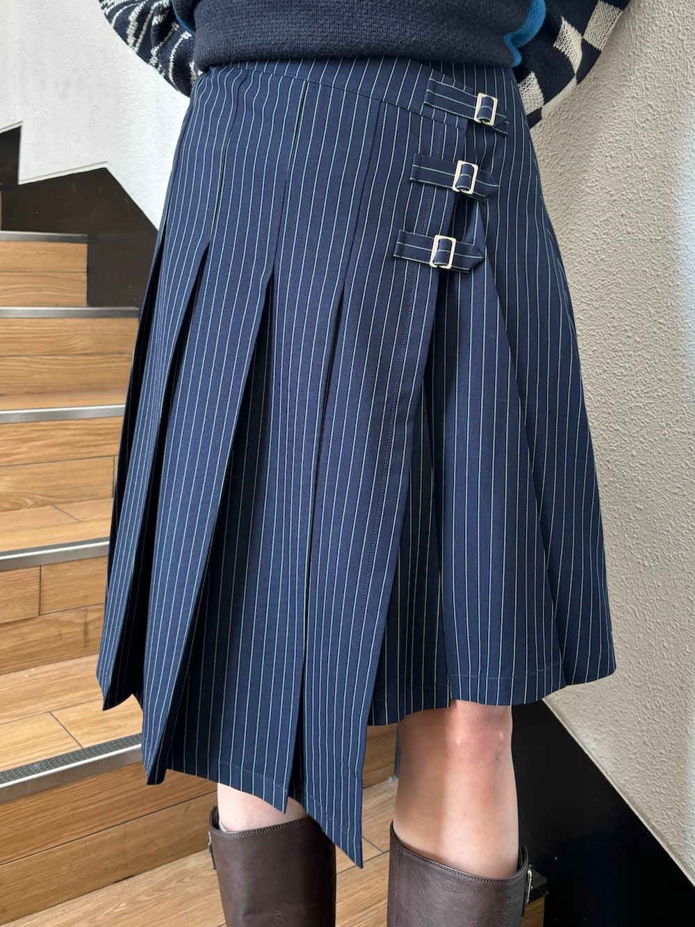 ブルー系のスカート、ゴールド系のハンドバッグ、ブラック系のニット/セーターを着用したレディースの夏コーディネートの8枚目の写真