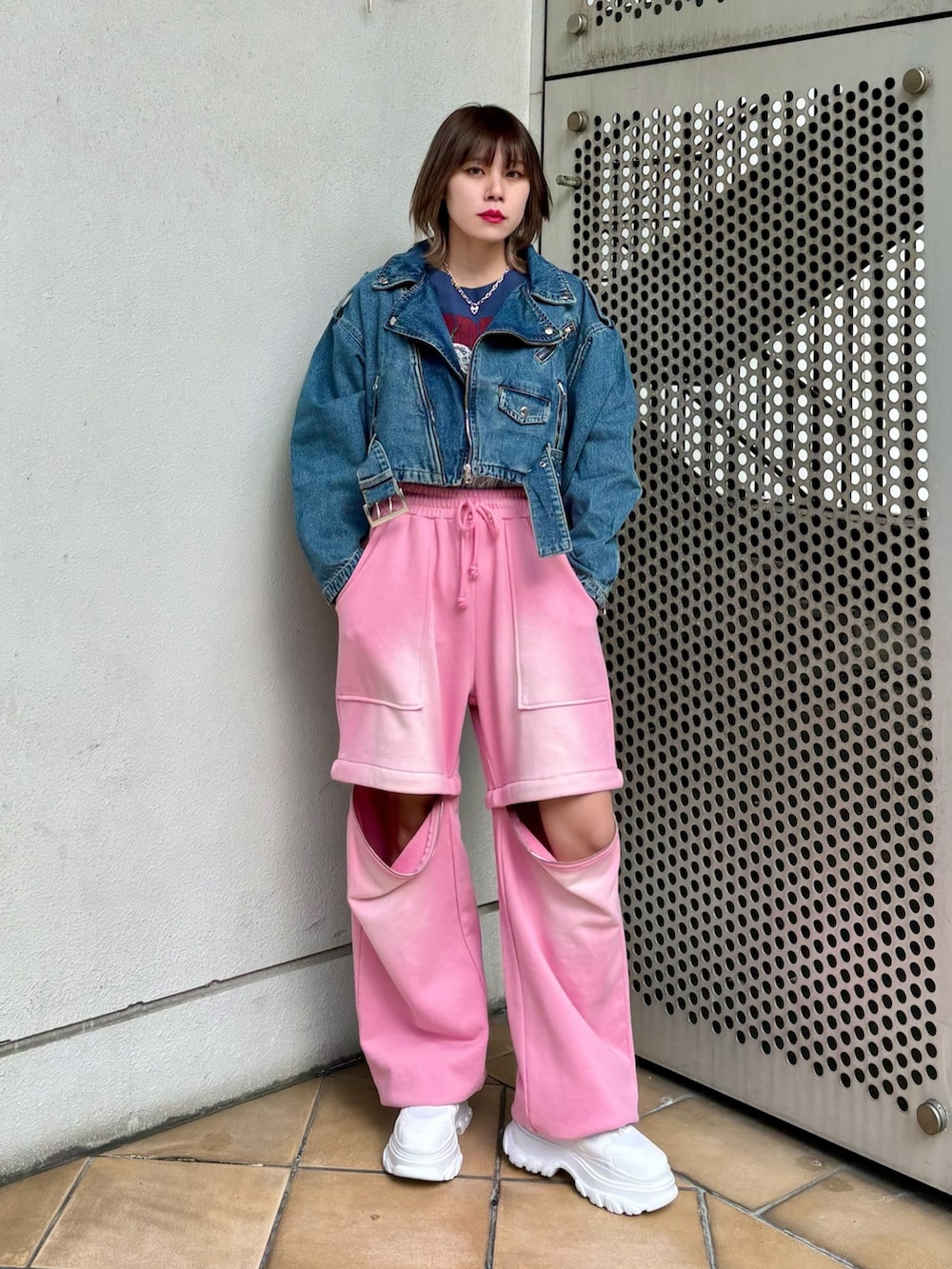 ホワイト系のスニーカー、ピンク系のスウェットパンツ、ブルー系のライダースジャケットを着用したレディースの春コーディネートの3枚目の写真