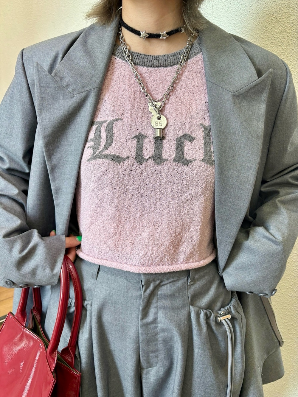 レッド系のハンドバッグ、レッド系のドレスシューズ、グレー系のテーラードジャケットを着用したレディースの夏コーディネートの8枚目の写真