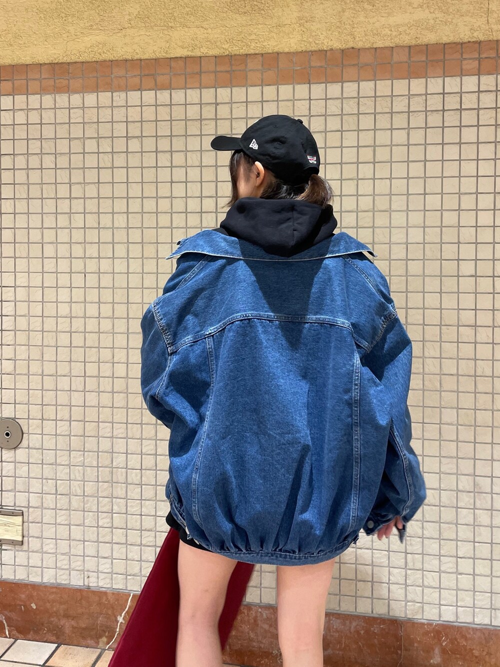 レッド系のトートバッグ、ブルー系のデニムジャケット、ブラック系のブーツを着用したレディースの冬コーディネートの6枚目の写真