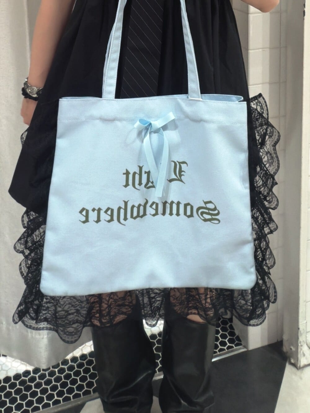 ブルー系のトートバッグ、ブラック系のワンピース、ブラック系のネクタイを着用したレディースの夏コーディネートの6枚目の写真