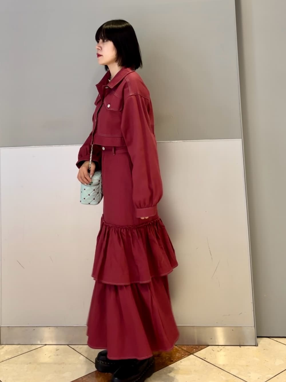 レッド系のワンピース、ブルー系のショルダーバッグ、ブラック系のネックレスを着用したレディースの秋コーディネートの5枚目の写真