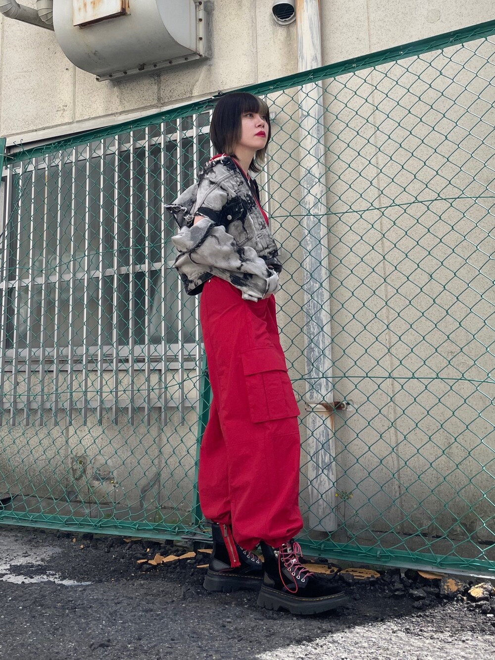 レッド系のカーゴパンツ、ブラック系のブーツ、ブラック系のデニムジャケットを着用したレディースの春コーディネートの6枚目の写真