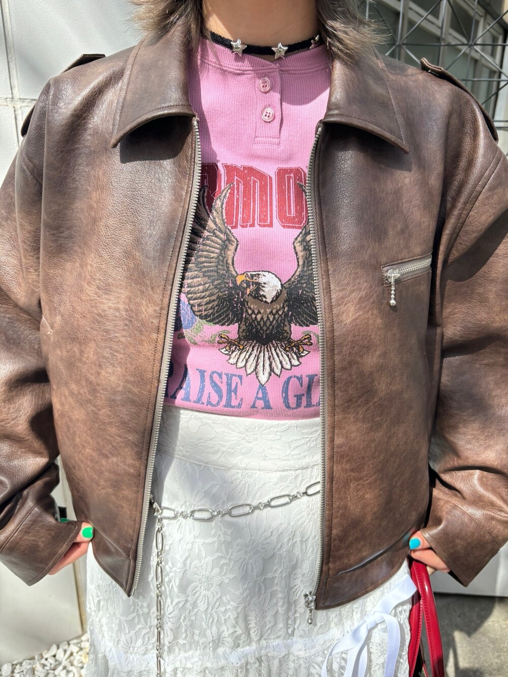 レッド系のハンドバッグ、レッド系のパンプス、ブラウン系のブルゾンを着用したレディースの夏コーディネートの6枚目の写真