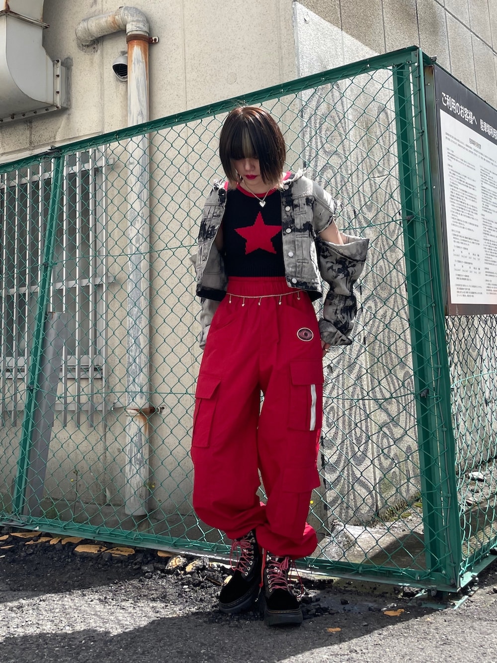 レッド系のカーゴパンツ、ブラック系のブーツ、ブラック系のデニムジャケットを着用したレディースの春コーディネートの3枚目の写真