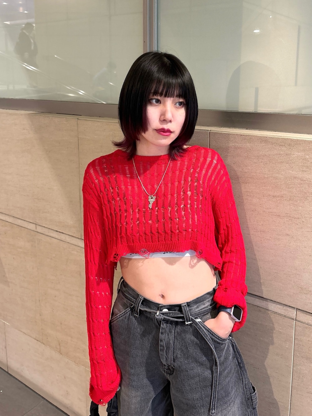 ブラック系のデニムパンツ、ブラック系のショルダーバッグ、レッド系のニット/セーターを着用したレディースの春コーディネートの5枚目の写真