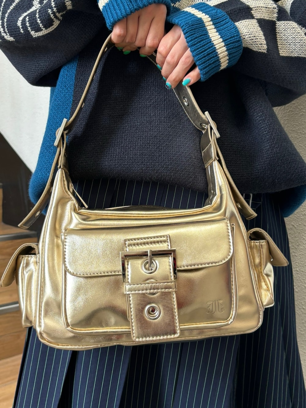 ブルー系のスカート、ゴールド系のハンドバッグ、ブラック系のニット/セーターを着用したレディースの夏コーディネートの9枚目の写真