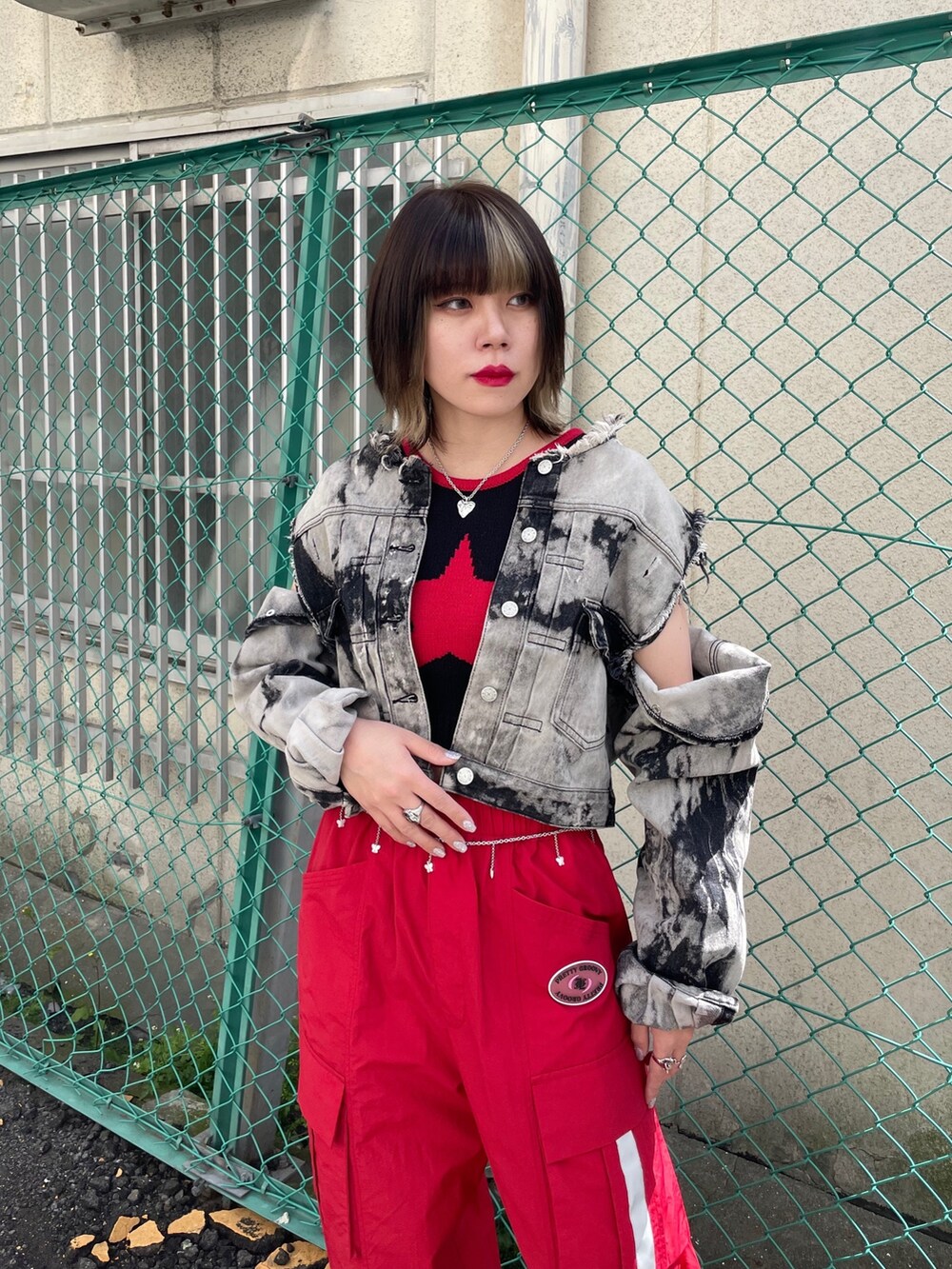 レッド系のカーゴパンツ、ブラック系のブーツ、ブラック系のデニムジャケットを着用したレディースの春コーディネートの5枚目の写真