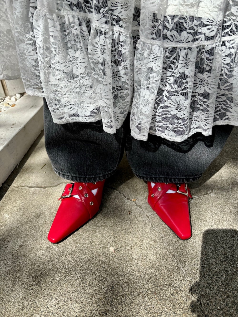 レッド系のハンドバッグ、レッド系のパンプス、ブラウン系のブルゾンを着用したレディースの夏コーディネートの9枚目の写真