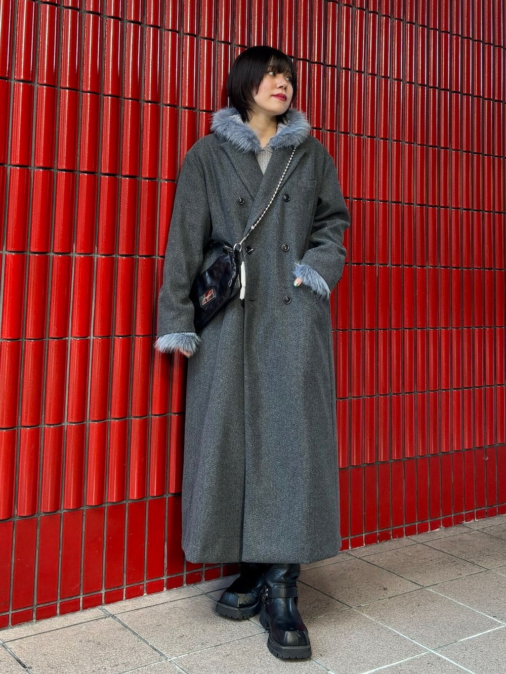 グレー系のチェスターコート、ブラック系のブーツ、ブラック系のハンドバッグを着用したレディースの冬コーディネートの2枚目の写真