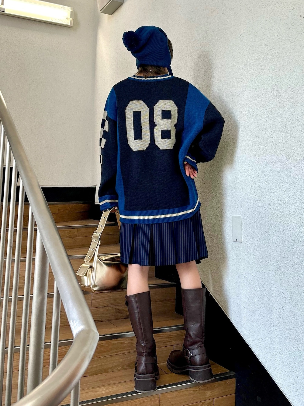 ブルー系のスカート、ゴールド系のハンドバッグ、ブラック系のニット/セーターを着用したレディースの夏コーディネートの3枚目の写真