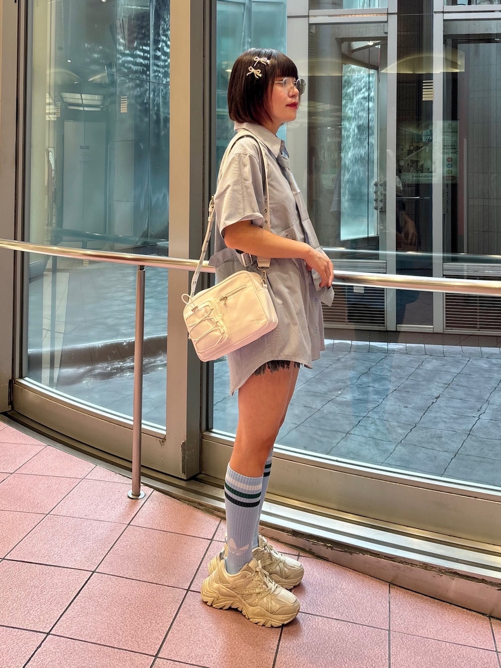 ブルー系のシャツ/ブラウス、ホワイト系のショルダーバッグ、ブラック系のデニムパンツを着用したレディースの夏コーディネートの3枚目の写真