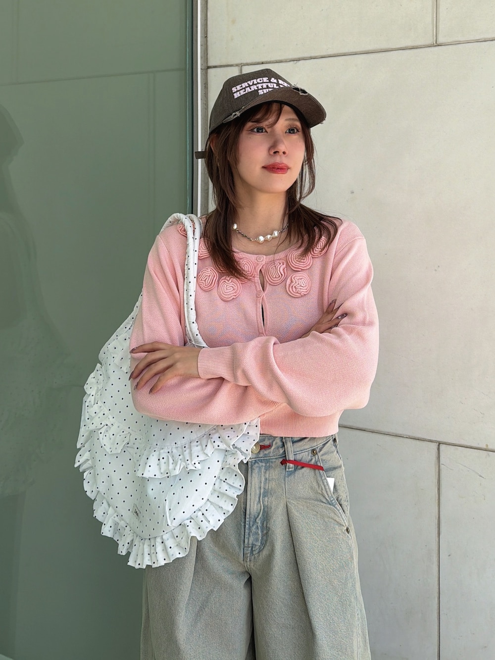 ピンク系のニット/セーター、ホワイト系のトートバッグ、ブルー系のデニムパンツを着用したレディースの春コーディネートの5枚目の写真