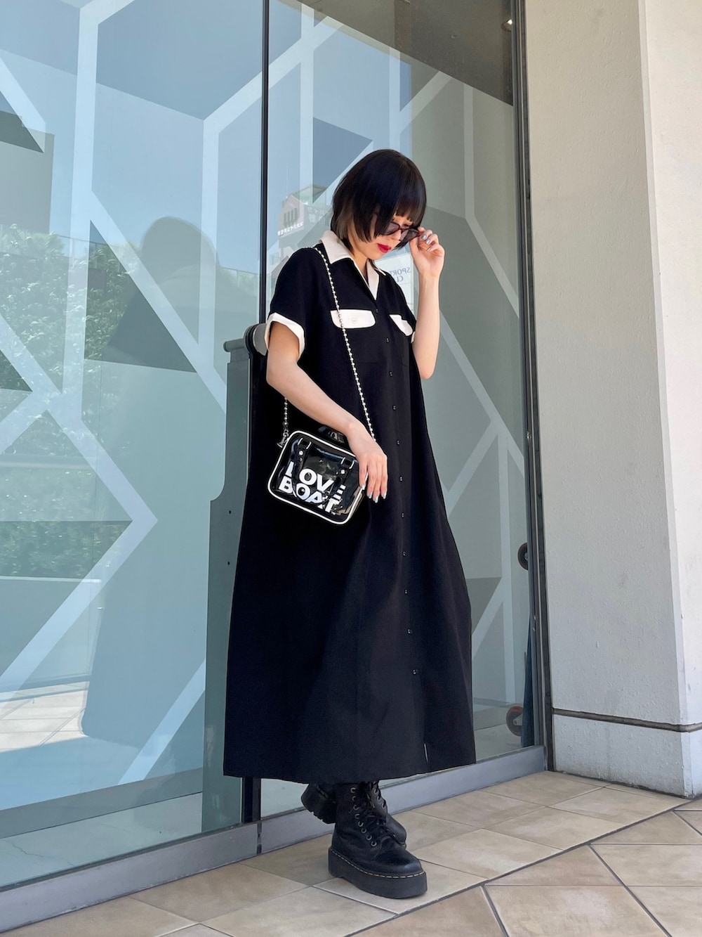 ブラック系のワンピース、ブラック系のボストンバッグ、レッド系のサングラスを着用したレディースの春コーディネートの2枚目の写真