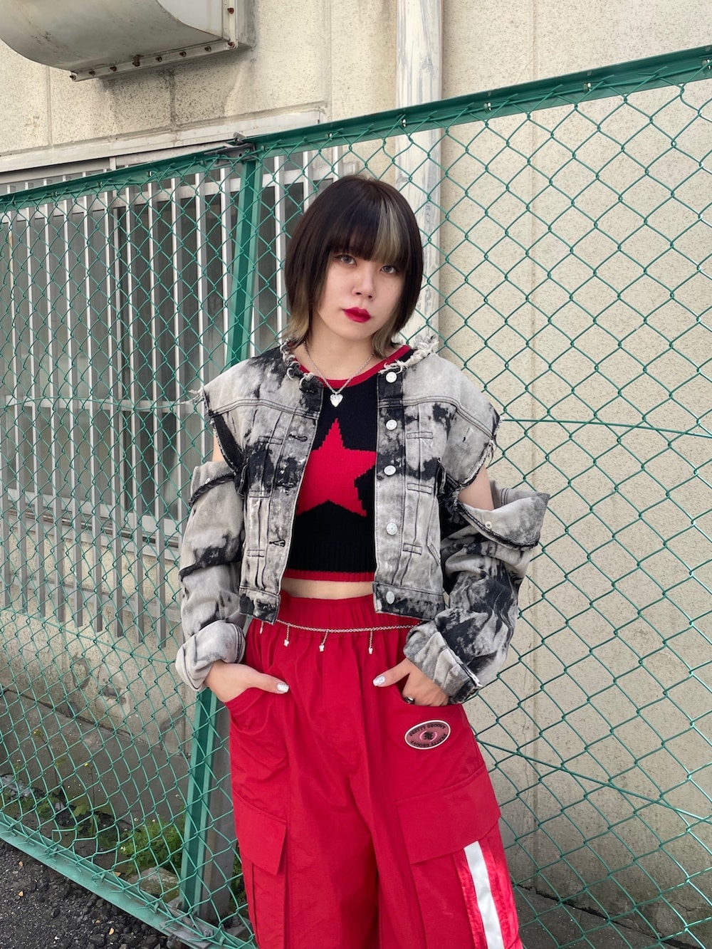 レッド系のカーゴパンツ、ブラック系のブーツ、ブラック系のデニムジャケットを着用したレディースの春コーディネートの4枚目の写真