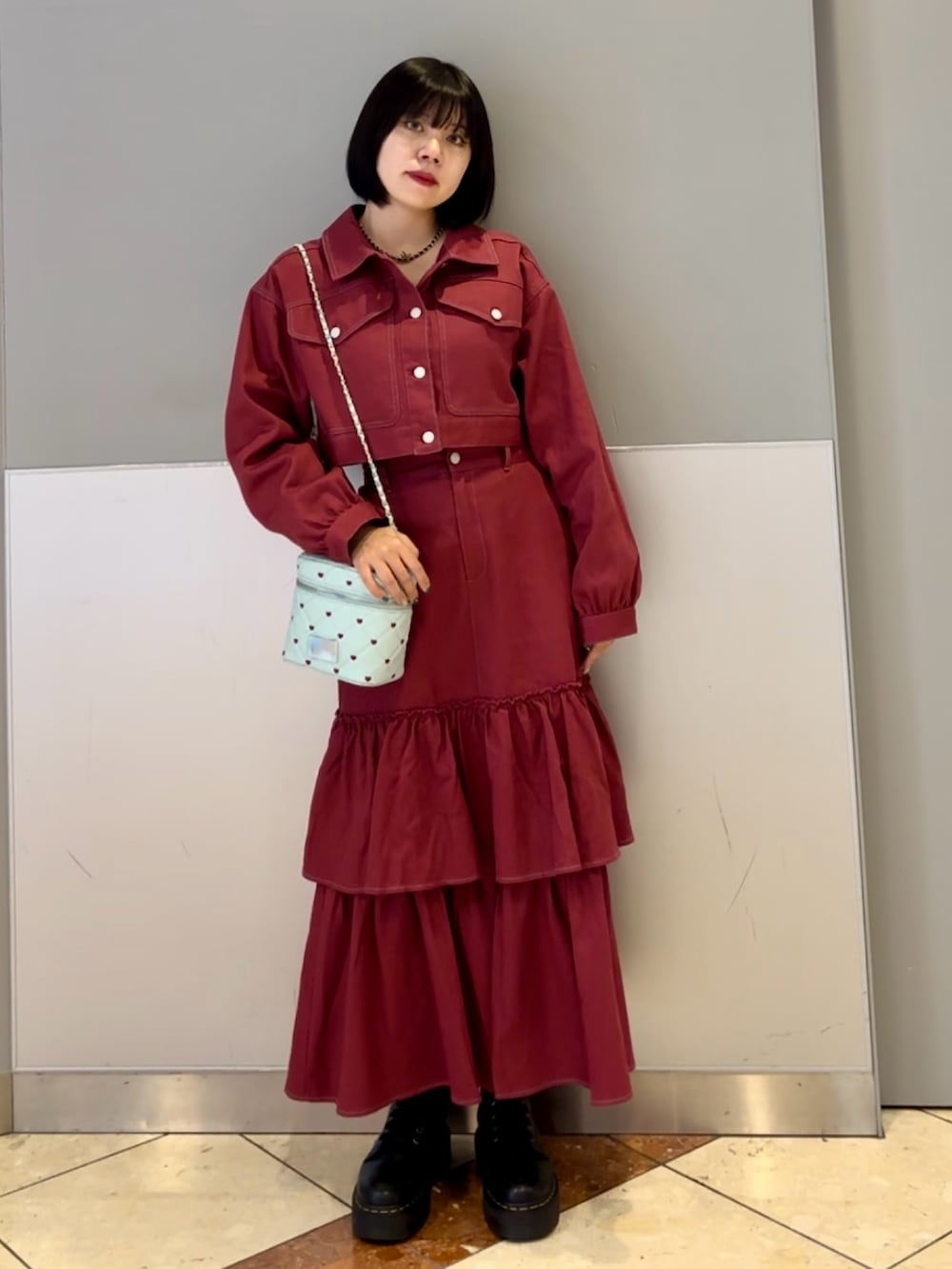 レッド系のワンピース、ブルー系のショルダーバッグ、ブラック系のネックレスを着用したレディースの秋コーディネートの3枚目の写真