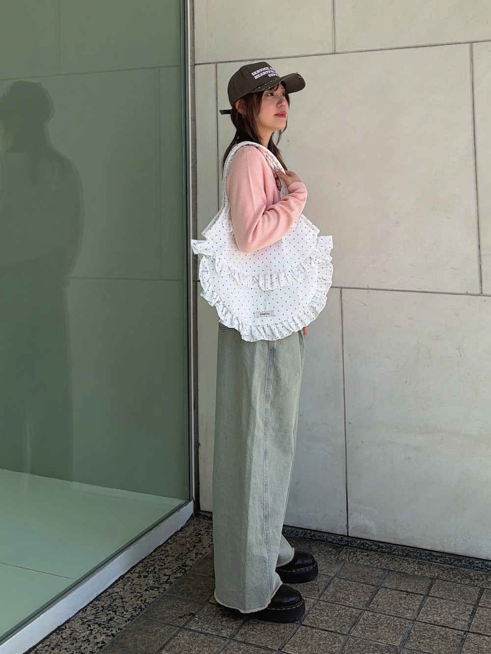 ピンク系のニット/セーター、ホワイト系のトートバッグ、ブルー系のデニムパンツを着用したレディースの春コーディネートの4枚目の写真