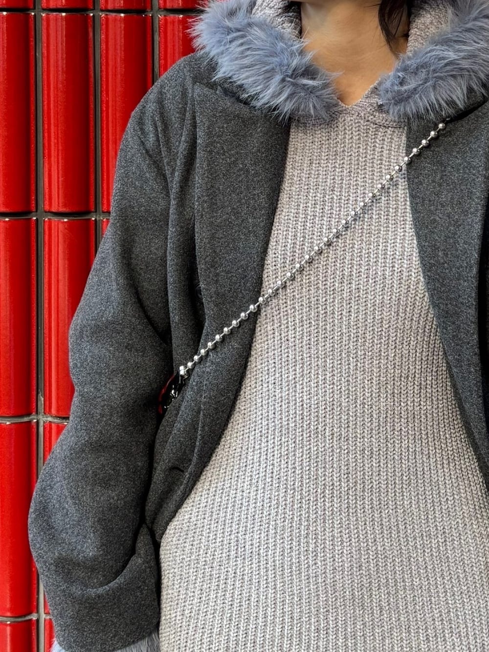 グレー系のチェスターコート、ブラック系のブーツ、ブラック系のハンドバッグを着用したレディースの冬コーディネートの9枚目の写真