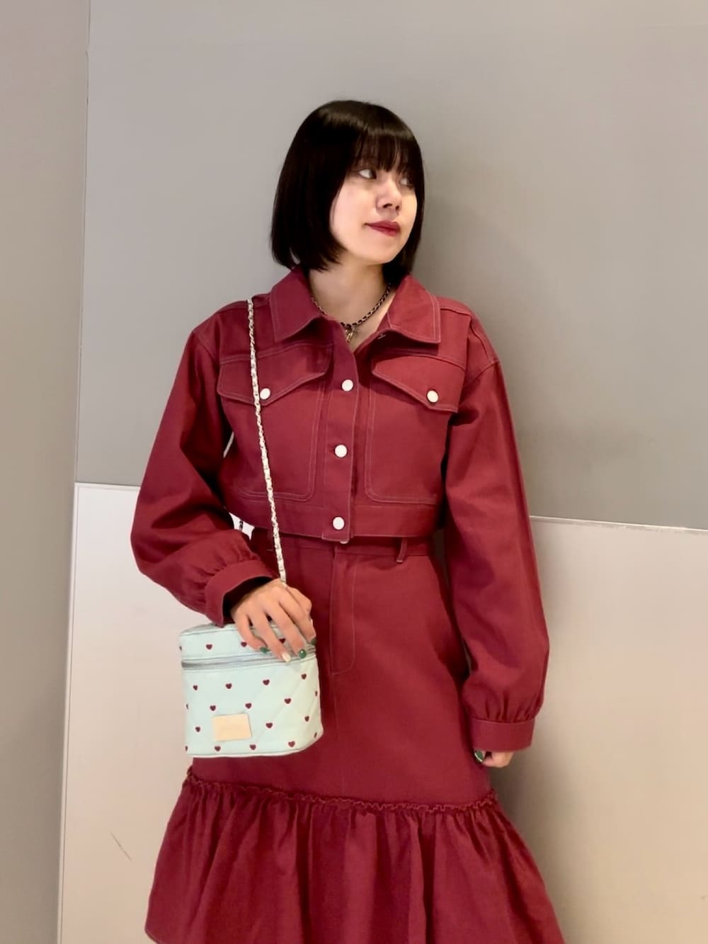 レッド系のワンピース、ブルー系のショルダーバッグ、ブラック系のネックレスを着用したレディースの秋コーディネートの6枚目の写真