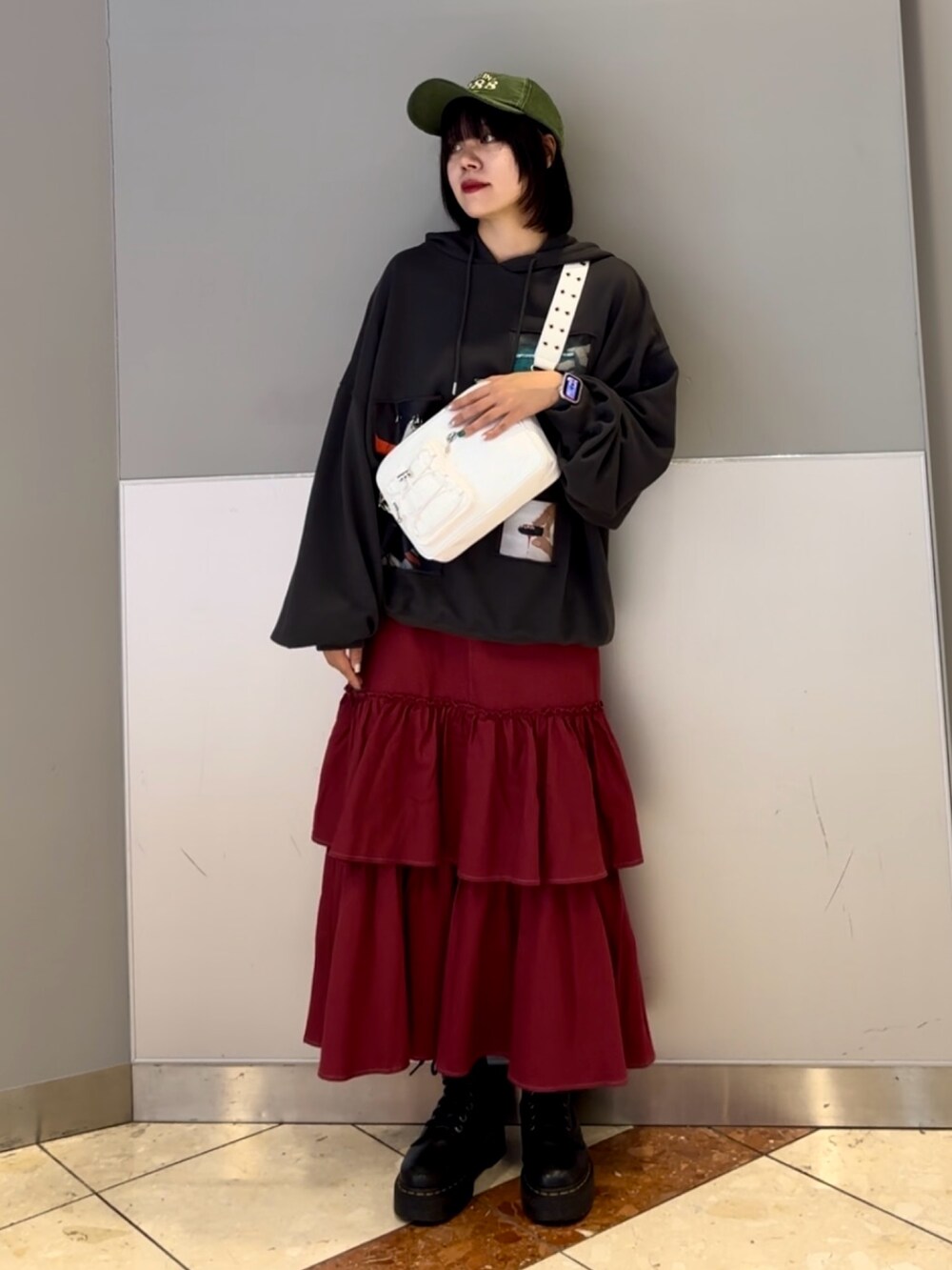 レッド系のワンピース、グレー系のパーカー、ホワイト系のショルダーバッグを着用したレディースの秋コーディネートの2枚目の写真