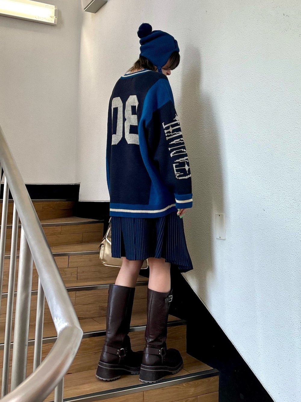 ブルー系のスカート、ゴールド系のハンドバッグ、ブラック系のニット/セーターを着用したレディースの夏コーディネートの4枚目の写真