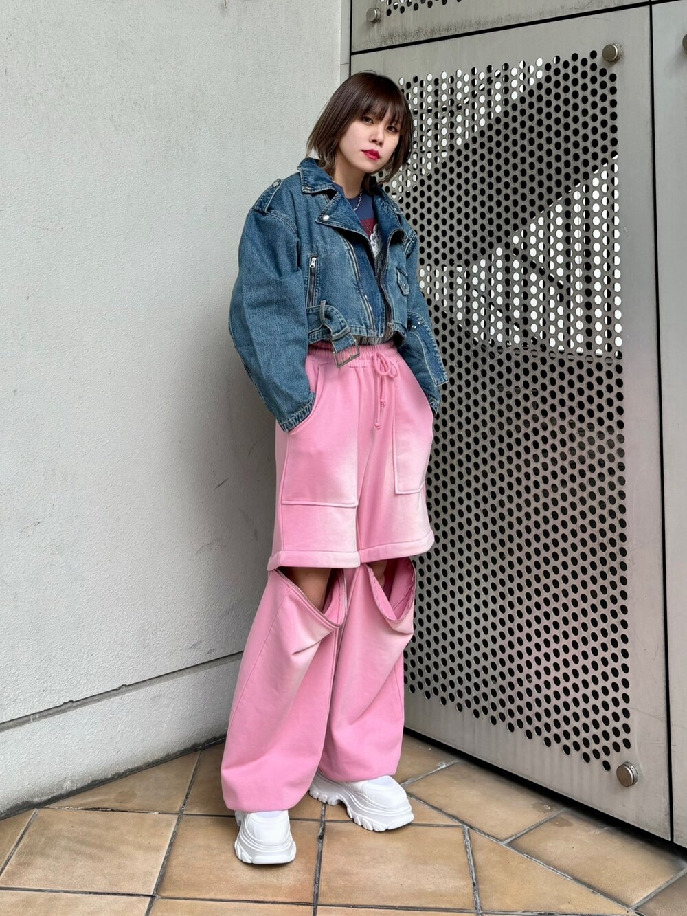 ホワイト系のスニーカー、ピンク系のスウェットパンツ、ブルー系のライダースジャケットを着用したレディースの春コーディネートの4枚目の写真