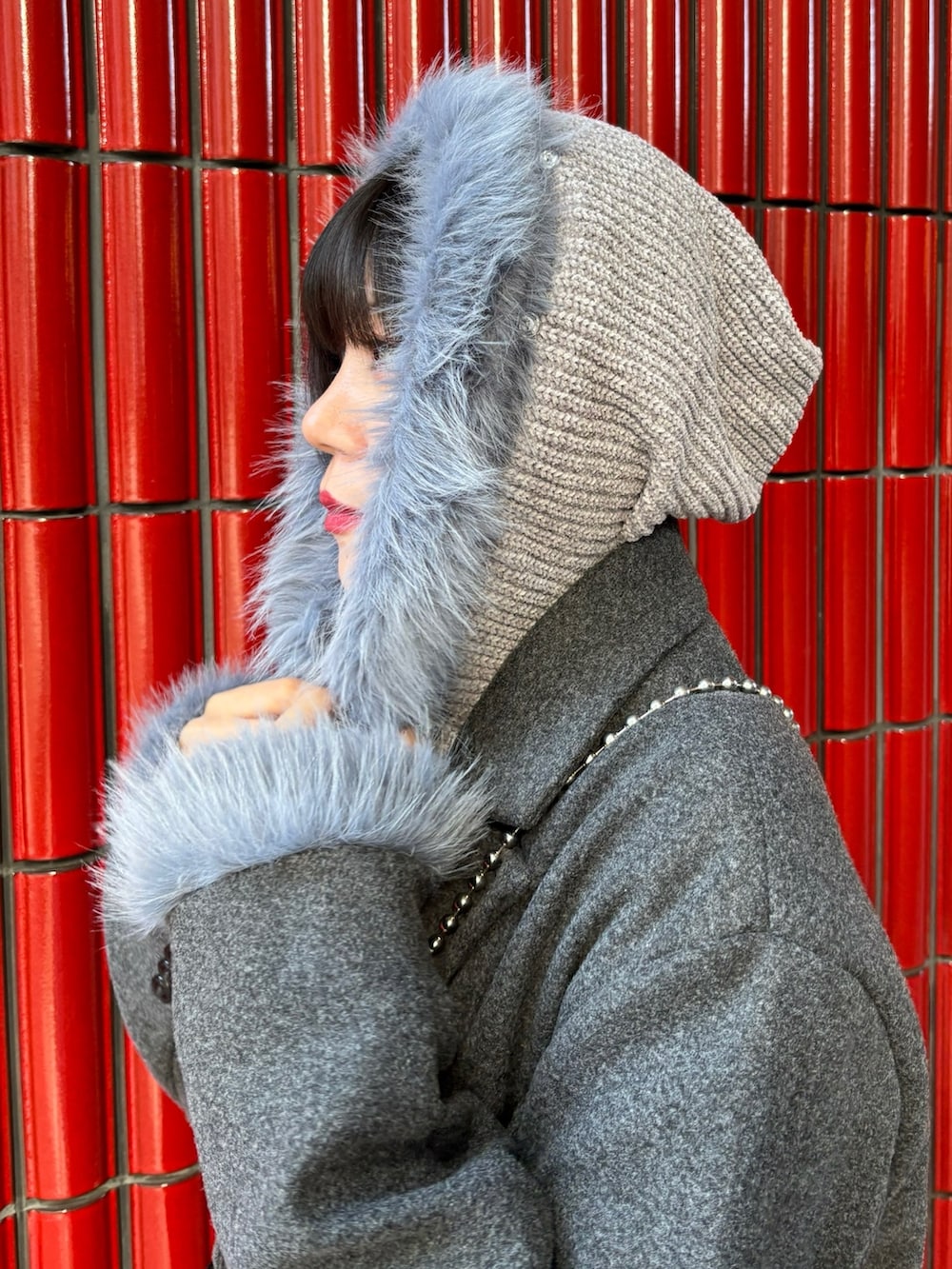 グレー系のチェスターコート、ブラック系のブーツ、ブラック系のハンドバッグを着用したレディースの冬コーディネートの7枚目の写真