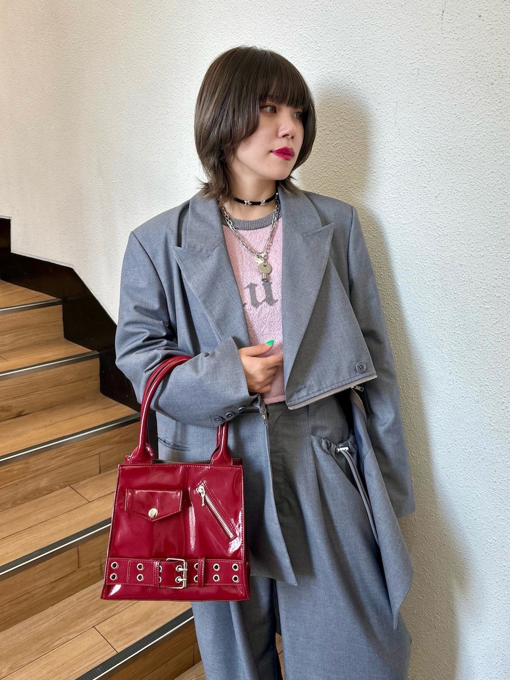 レッド系のハンドバッグ、レッド系のドレスシューズ、グレー系のテーラードジャケットを着用したレディースの夏コーディネートの7枚目の写真
