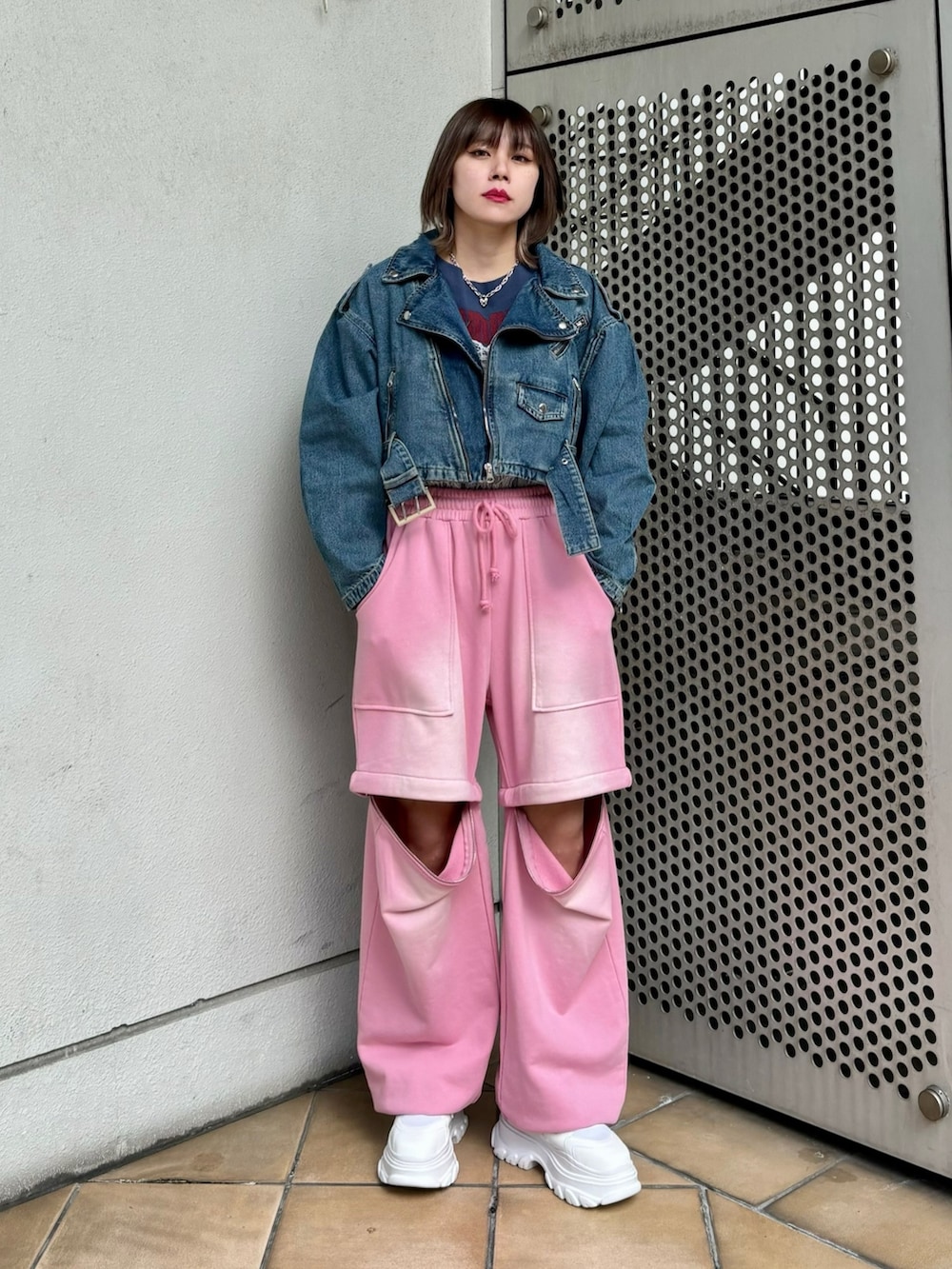ホワイト系のスニーカー、ピンク系のスウェットパンツ、ブルー系のライダースジャケットを着用したレディースの春コーディネートの2枚目の写真