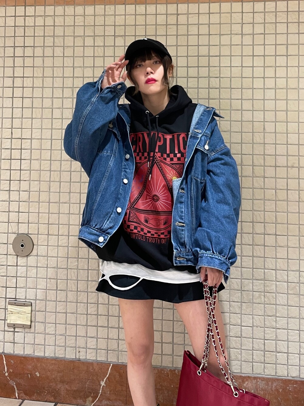 レッド系のトートバッグ、ブルー系のデニムジャケット、ブラック系のブーツを着用したレディースの冬コーディネートの4枚目の写真