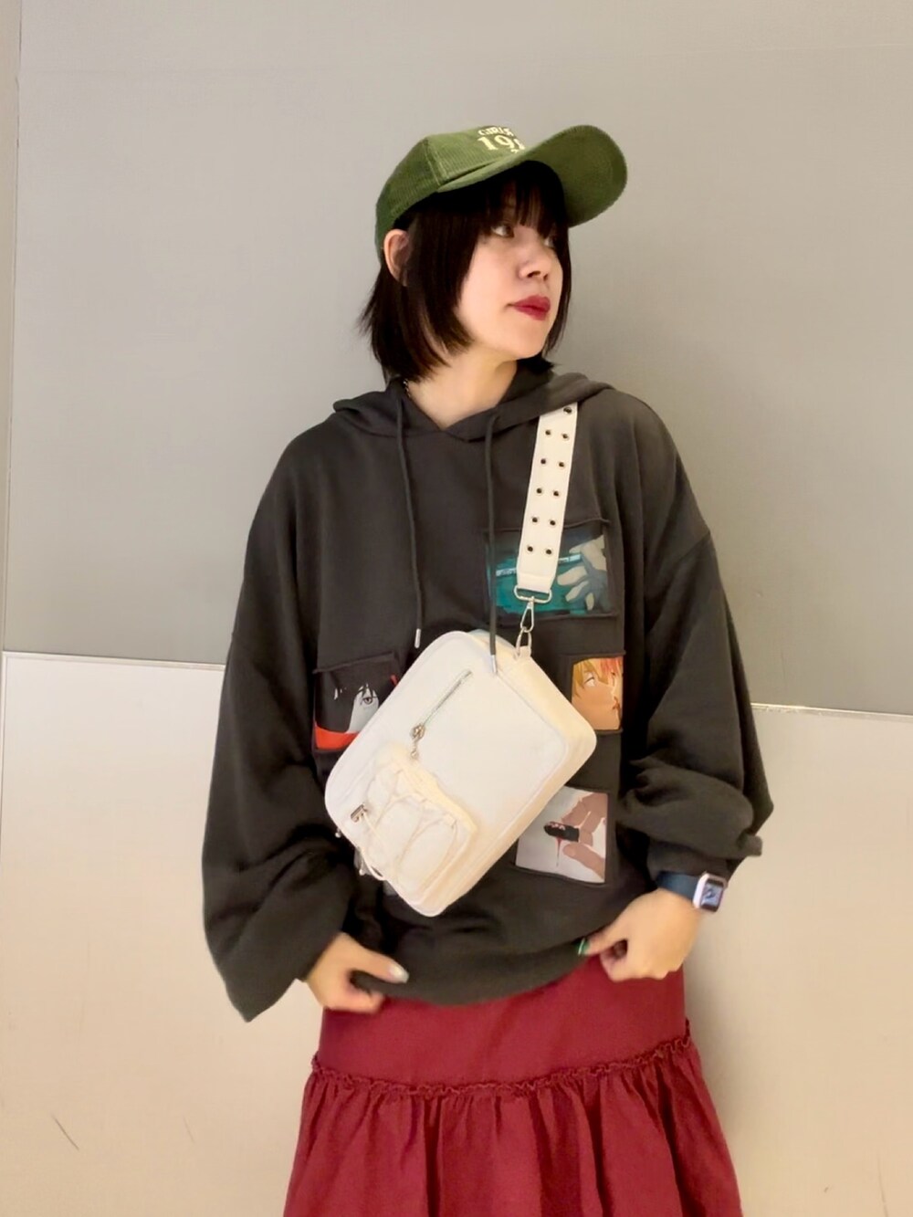 レッド系のワンピース、グレー系のパーカー、ホワイト系のショルダーバッグを着用したレディースの秋コーディネートの6枚目の写真