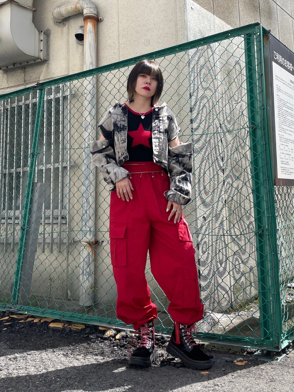 レッド系のカーゴパンツ、ブラック系のブーツ、ブラック系のデニムジャケットを着用したレディースの春コーディネートの7枚目の写真