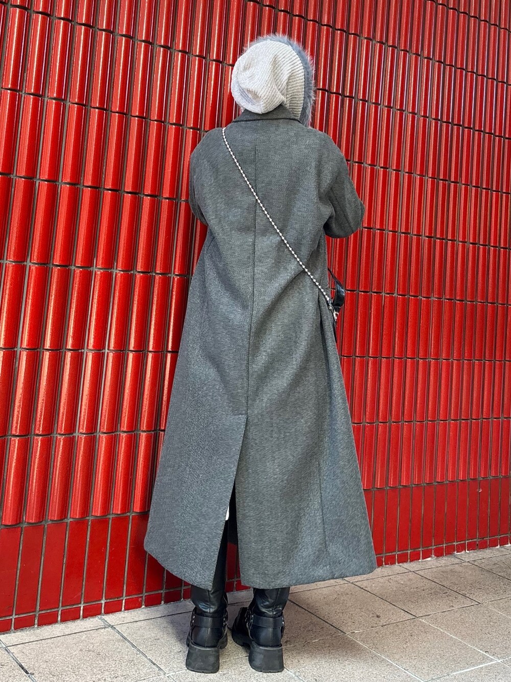 グレー系のチェスターコート、ブラック系のブーツ、ブラック系のハンドバッグを着用したレディースの冬コーディネートの4枚目の写真