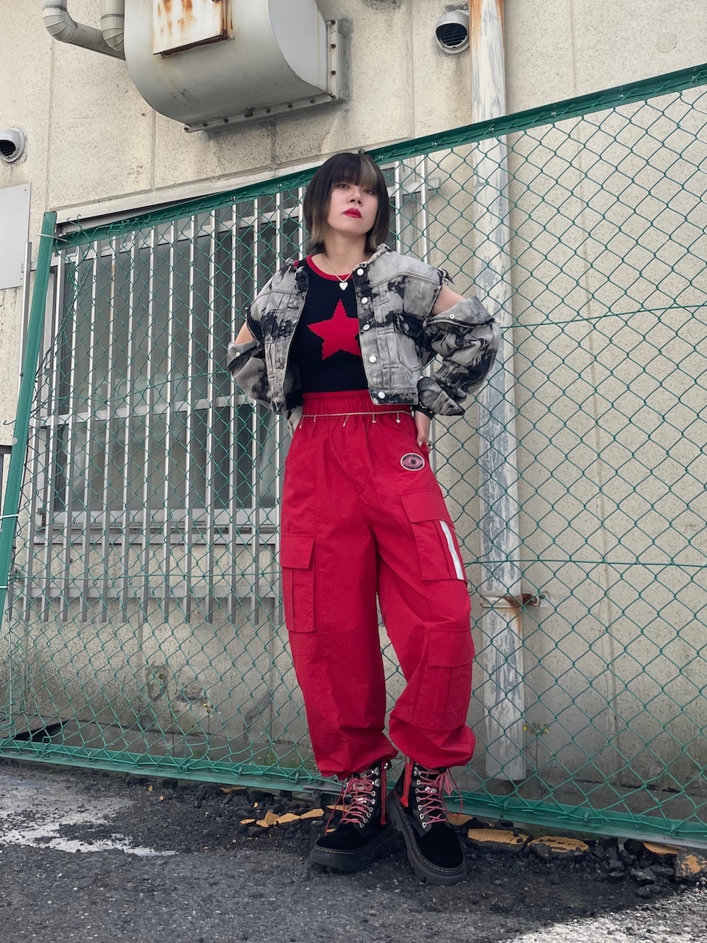 レッド系のカーゴパンツ、ブラック系のブーツ、ブラック系のデニムジャケットを着用したレディースの春コーディネートの8枚目の写真