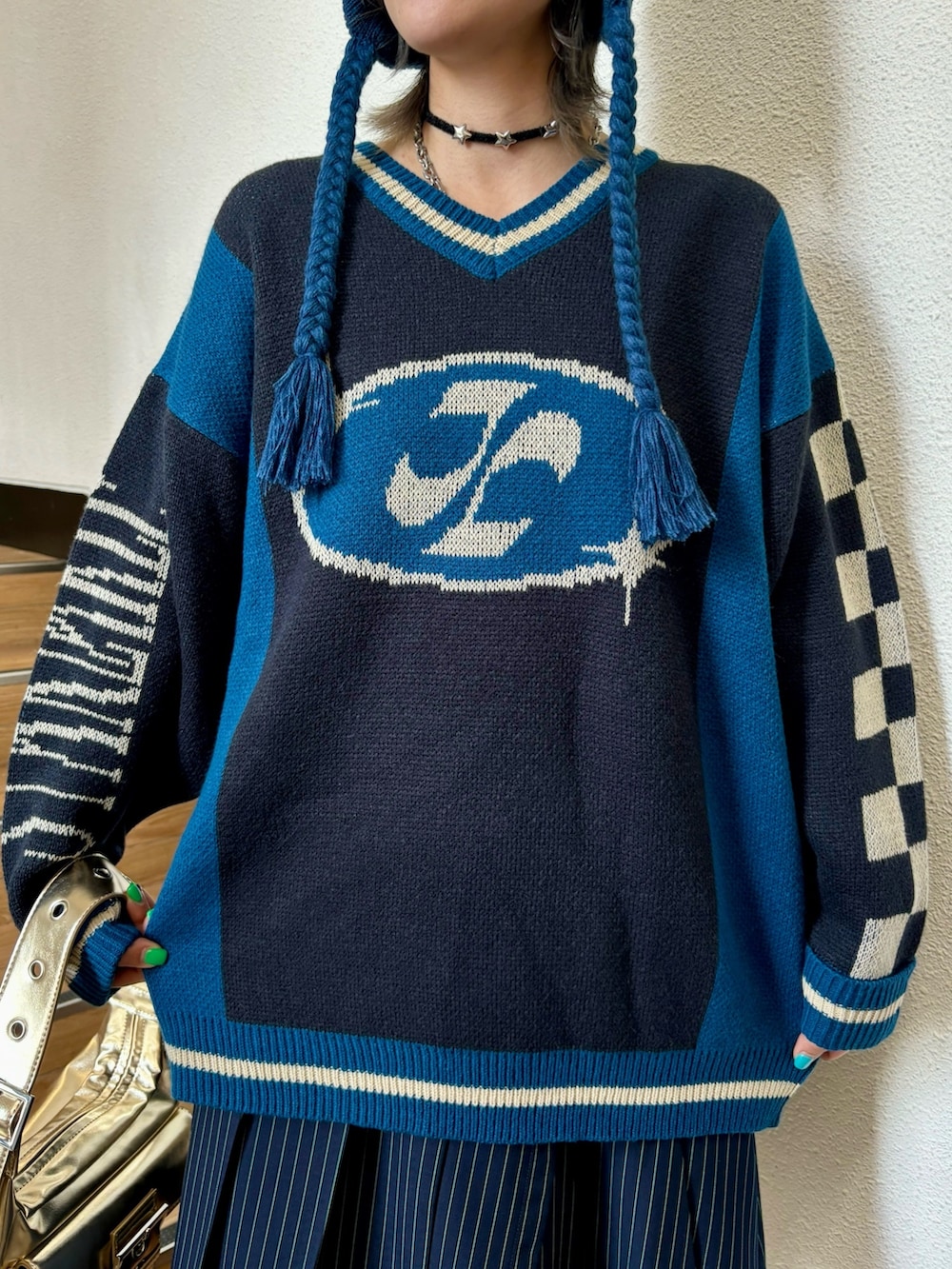 ブルー系のスカート、ゴールド系のハンドバッグ、ブラック系のニット/セーターを着用したレディースの夏コーディネートの6枚目の写真