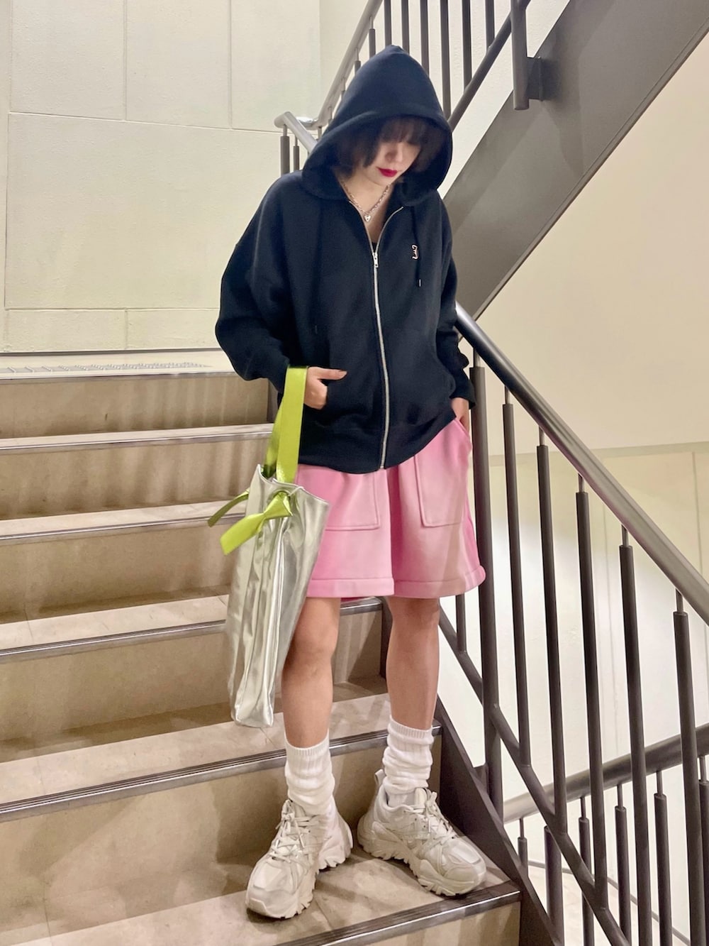 シルバー系のトートバッグ、ピンク系のスウェットパンツ、ブラック系のパーカーを着用したレディースの冬コーディネートの2枚目の写真