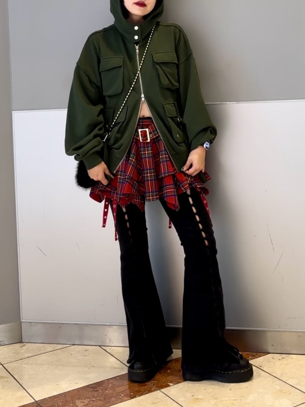 ブラック系のハンドバッグ、ブラック系のデニムパンツ、グリーン系のパーカーを着用したレディースの秋コーディネートの3枚目の写真