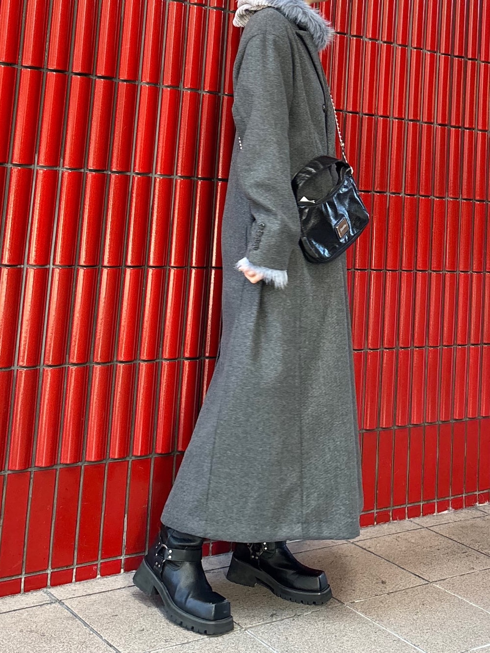 グレー系のチェスターコート、ブラック系のブーツ、ブラック系のハンドバッグを着用したレディースの冬コーディネートの3枚目の写真