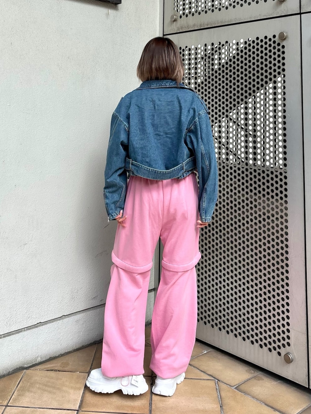 ホワイト系のスニーカー、ピンク系のスウェットパンツ、ブルー系のライダースジャケットを着用したレディースの春コーディネートの6枚目の写真