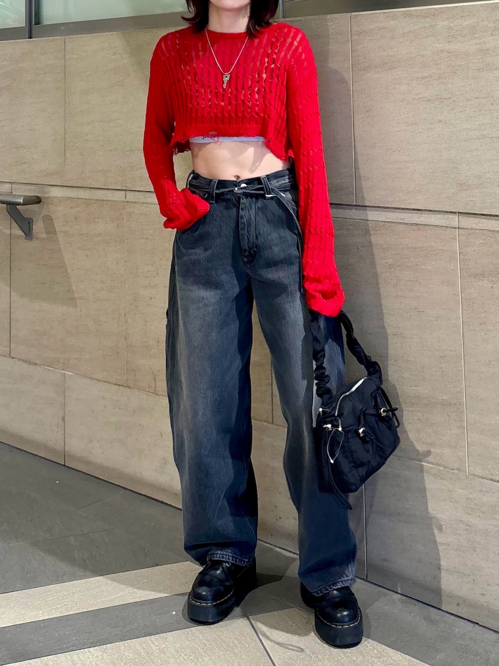 ブラック系のデニムパンツ、ブラック系のショルダーバッグ、レッド系のニット/セーターを着用したレディースの春コーディネートの3枚目の写真