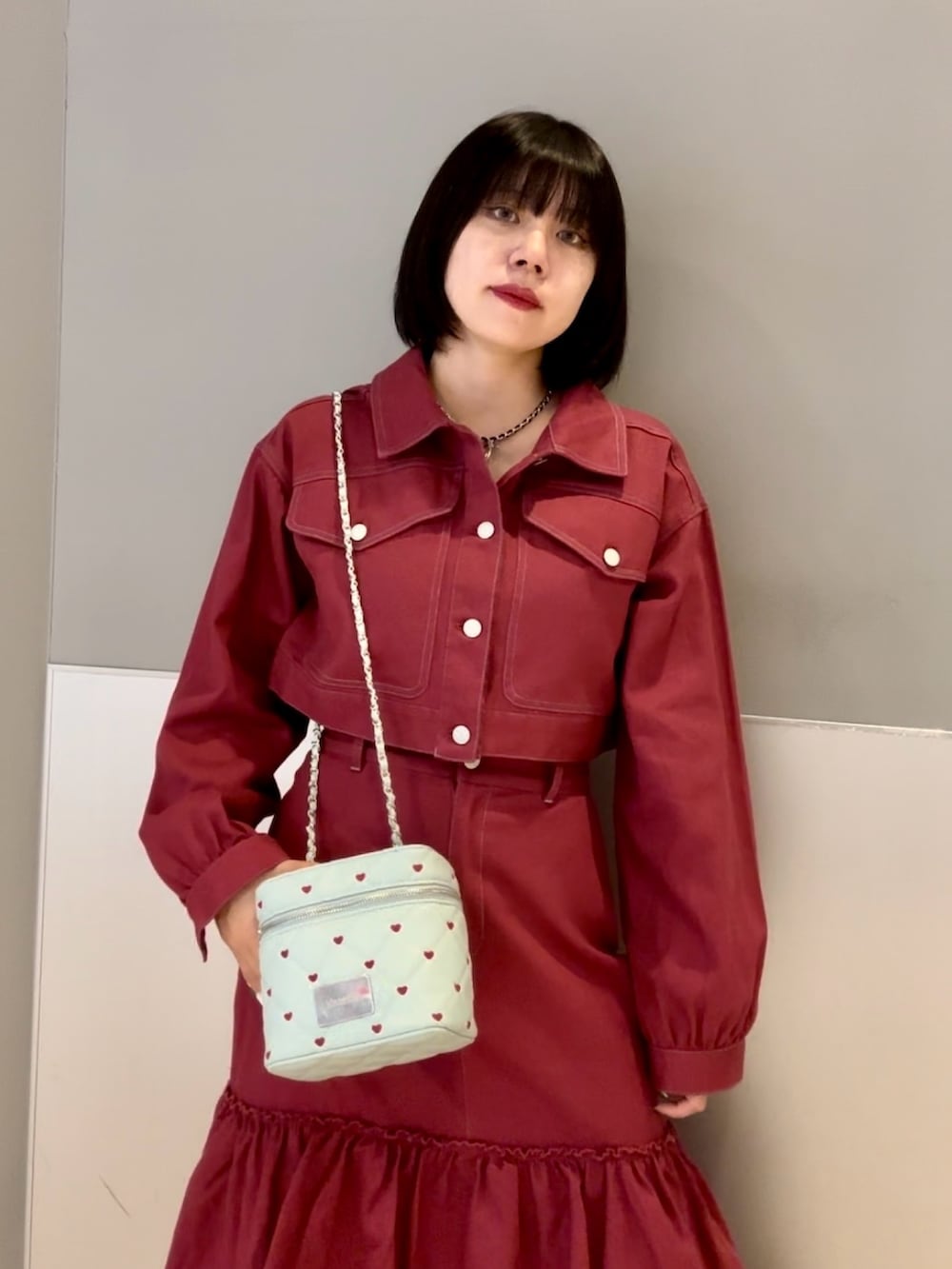 レッド系のワンピース、ブルー系のショルダーバッグ、ブラック系のネックレスを着用したレディースの秋コーディネートの7枚目の写真