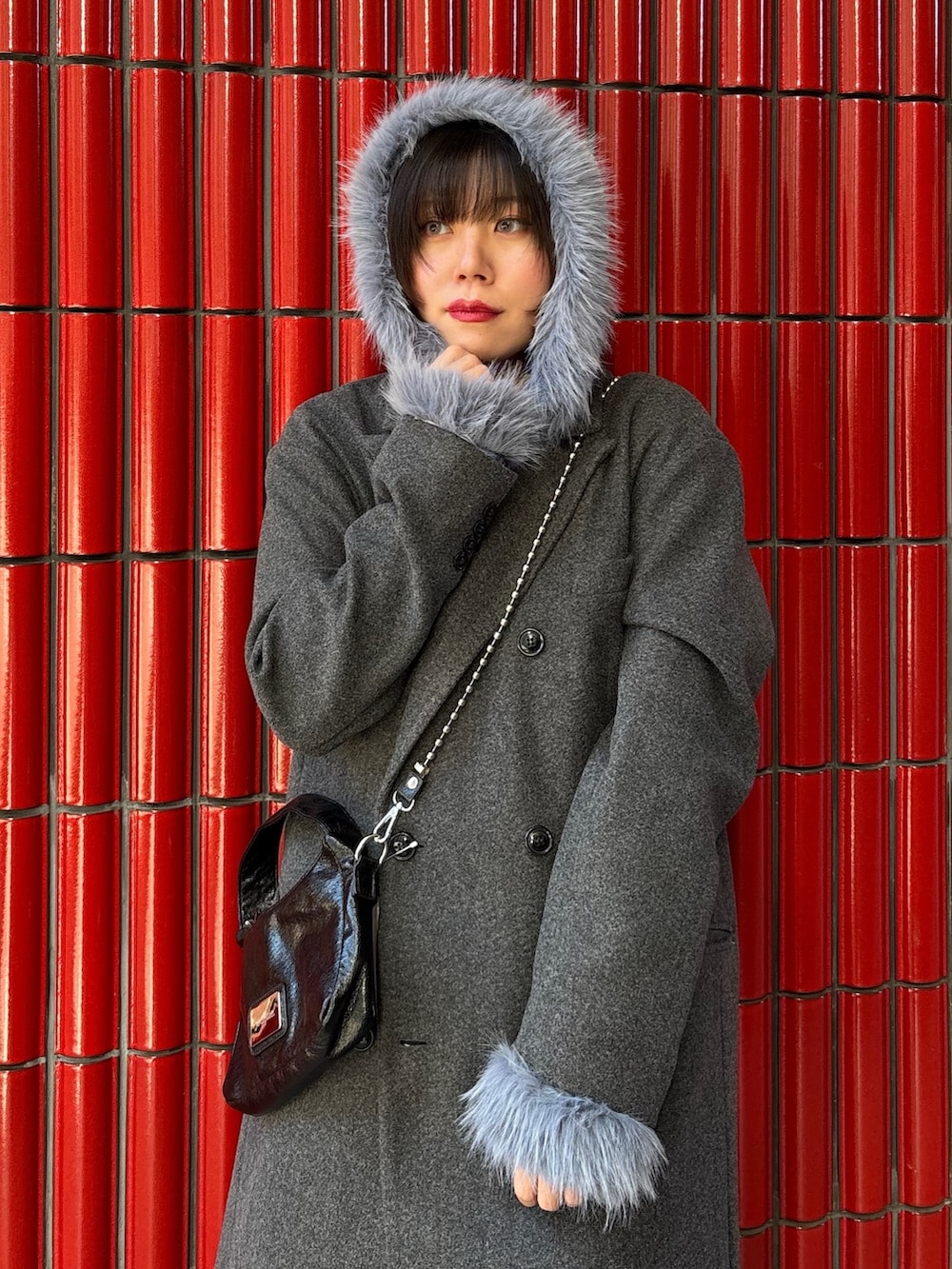 グレー系のチェスターコート、ブラック系のブーツ、ブラック系のハンドバッグを着用したレディースの冬コーディネートの5枚目の写真