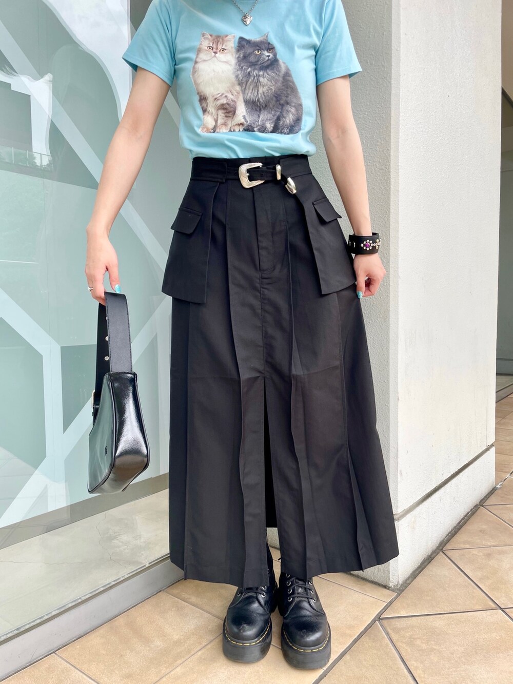 ブルー系のTシャツ/カットソー、ブラック系のスカート、シルバー系のハンドバッグを着用したレディースの春コーディネートの6枚目の写真