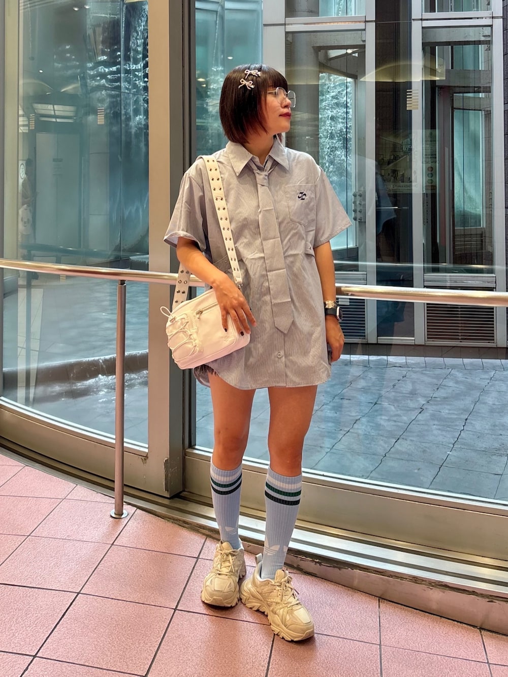 ブルー系のシャツ/ブラウス、ホワイト系のショルダーバッグ、ブラック系のデニムパンツを着用したレディースの夏コーディネートの2枚目の写真