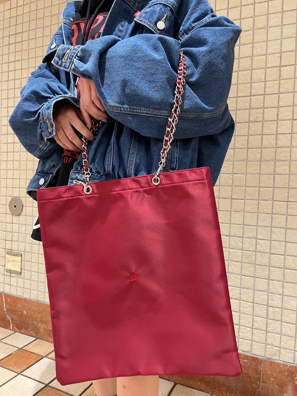 レッド系のトートバッグ、ブルー系のデニムジャケット、ブラック系のブーツを着用したレディースの冬コーディネートの7枚目の写真