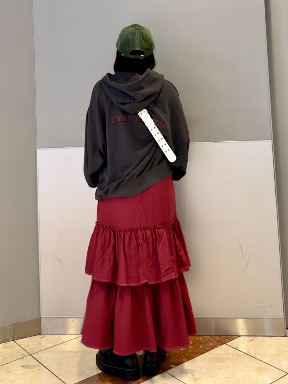 レッド系のワンピース、グレー系のパーカー、ホワイト系のショルダーバッグを着用したレディースの秋コーディネートの4枚目の写真